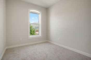 A room with a window showing a view of a building and a clear sky.